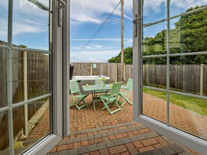 A patio with a table and chairs, a hot tub, and a wooden fence. - 2 Bed in Abergele (oc-89413) (Betws-yn-Rhos)