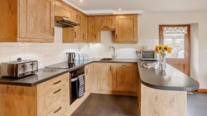 Eine moderne Küche mit Holzschränken, einem Backofen, einer Spüle und einer Mikrowelle.