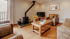 Ein Wohnzimmer mit Kamin, Fernseher, Sofa, Couchtisch und einem gerahmten Bild an der Wand.