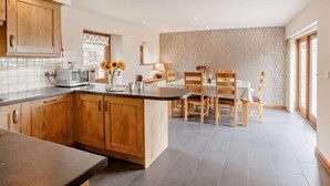 Eine moderne Küche mit Holzausbau, einer zentralen Kochinsel und einem Essbereich mit Stühlen und Tisch.