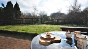 A table with a glass top and a view of a grassy yard with a wooden fence and trees. - 1 Bed in Bodmin (oc-brilo) (Tredinnick Pits)
