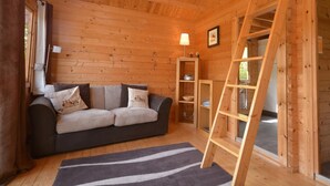 A wooden cabin interior with a sofa, a ladder, and a small shelf with dishes. - 1 Bed in Bodmin (oc-brilo) (Tredinnick Pits)