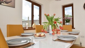 Un'area pranzo con un tavolo bianco, sedie e un vaso con fiori.