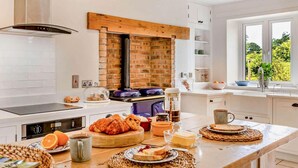 A modern kitchen with a brick wall, white cabinetry, and a large window. - 3 Bed in Kingsbridge (oc-court) (South Huish)