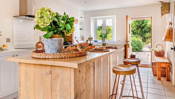 A kitchen with a wooden island, a large potted plant, and a view to the outdoors. - 3 Bed in Kingsbridge (oc-court) (South Huish)