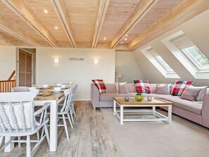 A room with a dining table, chairs, a sofa, and a coffee table. There are skylights and a view of the outdoors. - 3 Bed in Swanage (oc-dc063) (Worth Matravers)