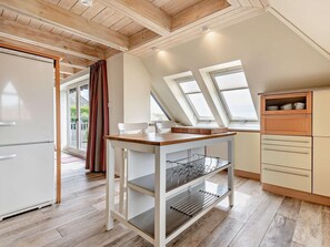 Eine moderne Küche mit Holzboden, Oberlichtern, einem weißen Kühlschrank und einem Holztisch mit Regalen.