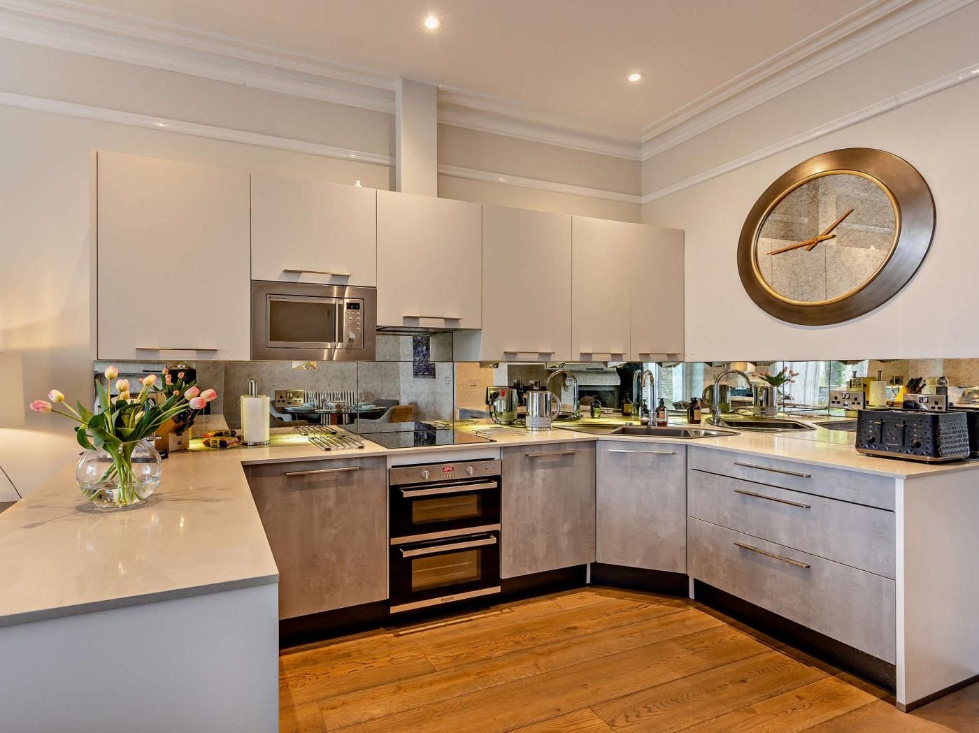 Una cocina moderna con una isla central, electrodomésticos de acero inoxidable y un gran reloj de pared.