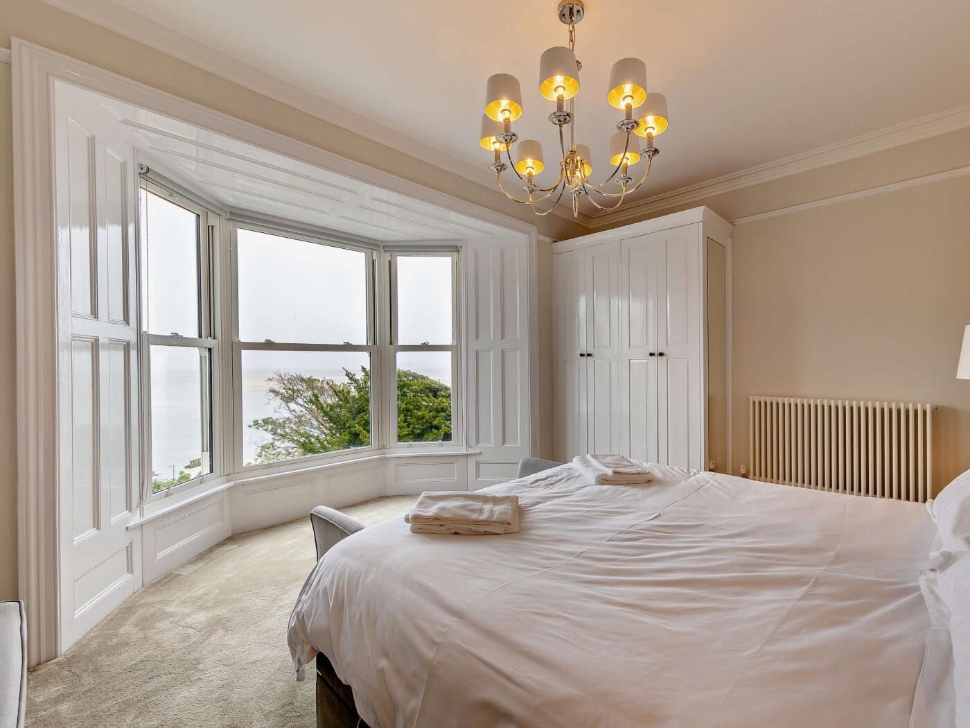 Una camera da letto con un letto grande, una finestra vista, un termosifone e un lampadario.