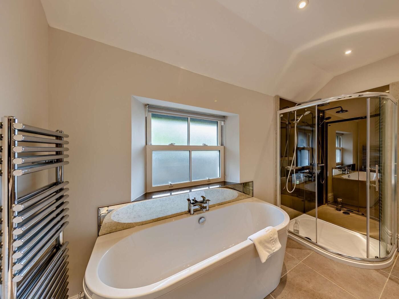 A modern bathroom with a freestanding bathtub, a glass-enclosed shower, and a window above the bathtub.