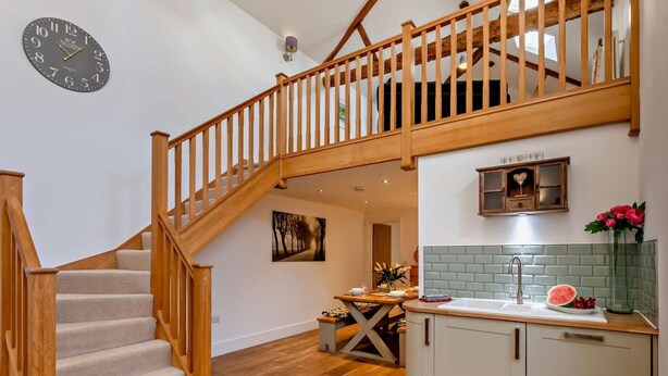 A staircase leading to an upper level, a kitchen with a tiled backsplash, and a clock on the wall. - 2 Bed in Settle (oc-g0051) (Settle)