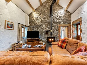 A cozy living room with a stone wall, a fireplace, a television, and a leather sofa. - 3 Bed in St Florence (oc-fb176) (Saint Florence)
