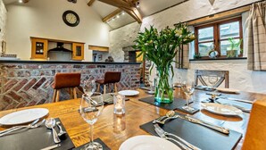 A dining area with a wooden table set for four, a stone wall, and a window with curtains. - 3 Bed in St Florence (oc-fb176) (Saint Florence)