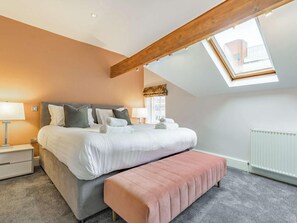 A bedroom with a large bed, a bench, a skylight, and a radiator. - 2 Bed in Harrogate (oc-hh029) (Harrogate)