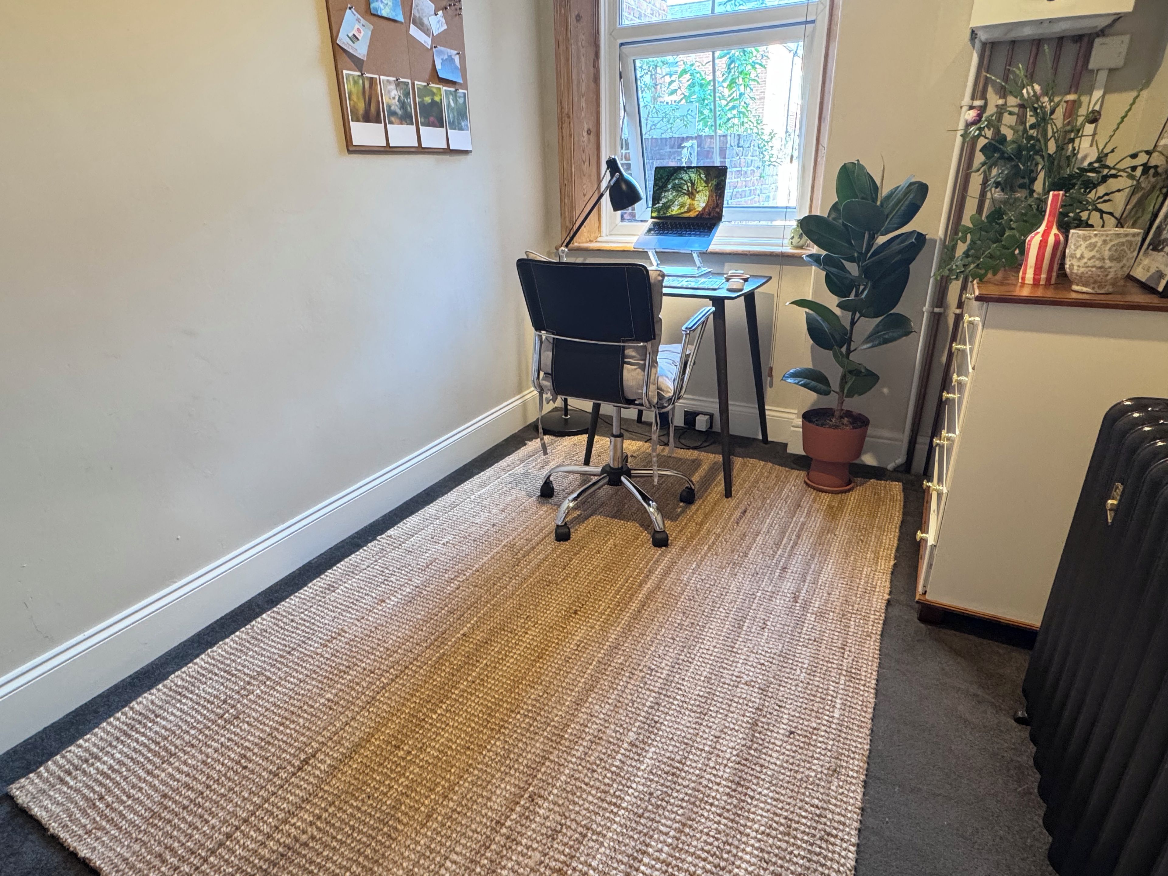 A small office space with a desk, chair, laptop, and a potted plant.