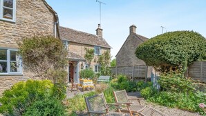 A stone house with a garden, outdoor seating, and a sign. - 2 Bed in Cirencester (oc-hic05) (Eastleach)