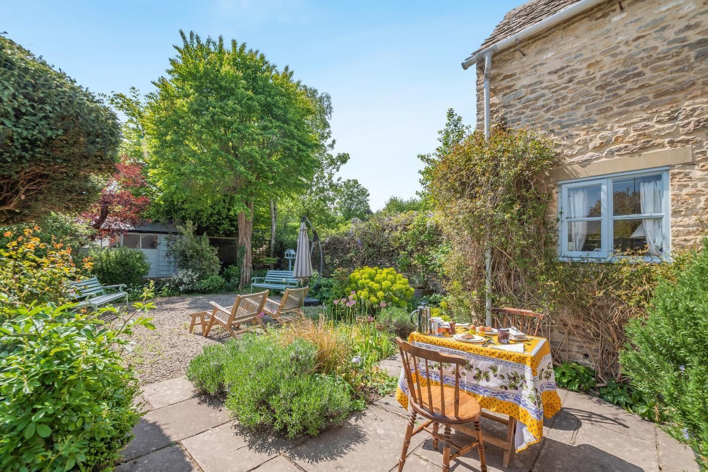 A stone building with a garden patio, outdoor seating, and a table set for dining.