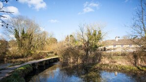 A river with a bridge, surrounded by trees and a building with multiple windows. - 2 Bed in Cirencester (oc-hic05) (Eastleach)