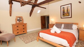 Een slaapkamer met een houten bed, een dressoir, een nachtkastje, een spiegel en een lijst met een foto van Australië.