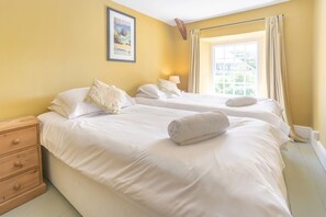 Ein Hotelzimmer mit zwei Betten, einem Holznachttisch und einem Fenster mit Vorhängen.