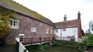 Ein traditionelles Backsteingebäude mit weißer Fassade, einer kleinen Brücke und einem Kanal.