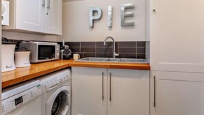 A modern kitchen with white cabinets, a microwave, a toaster, a sink, and a Bosch washing machine. - 2 Bed in Wells (oc-wesba) (Wookey Hole)
