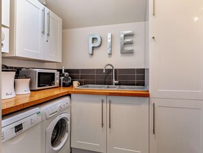 A modern kitchen with white cabinets, a microwave, a toaster, a sink, and a Bosch washing machine. - 2 Bed in Wells (oc-wesba) (Wookey Hole)