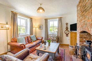 Ein gemütliches Wohnzimmer mit einem Ledersofa, einem Couchtisch und einem Kamin.