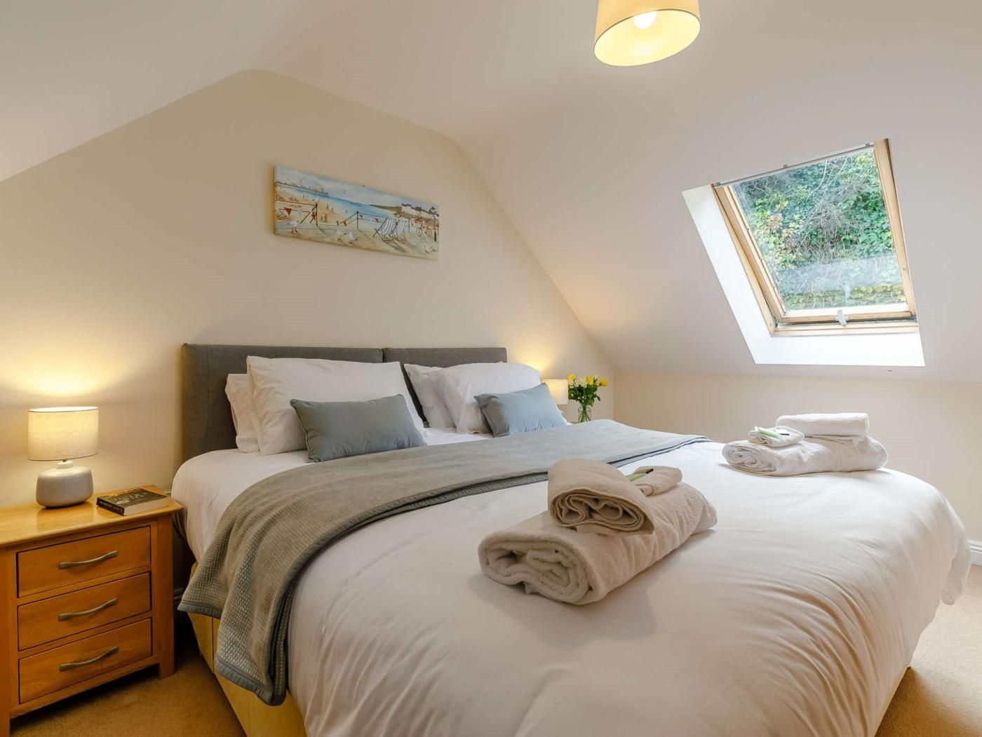 Ein Schlafzimmer mit Bett, Nachttisch, Lampe und einem Bild an der Wand.
