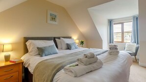 A bedroom with a bed, bedside table, lamp, and a window with a view. - 4 Bed in Redruth (oc-26386) (Portreath)