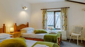 Habitación de hotel con dos camas, una silla, una ventana con cortinas, una lámpara y un radiador.