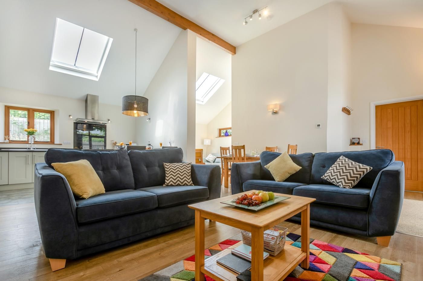 A modern living room with two dark sofas, a wooden coffee table, and a colorful rug.