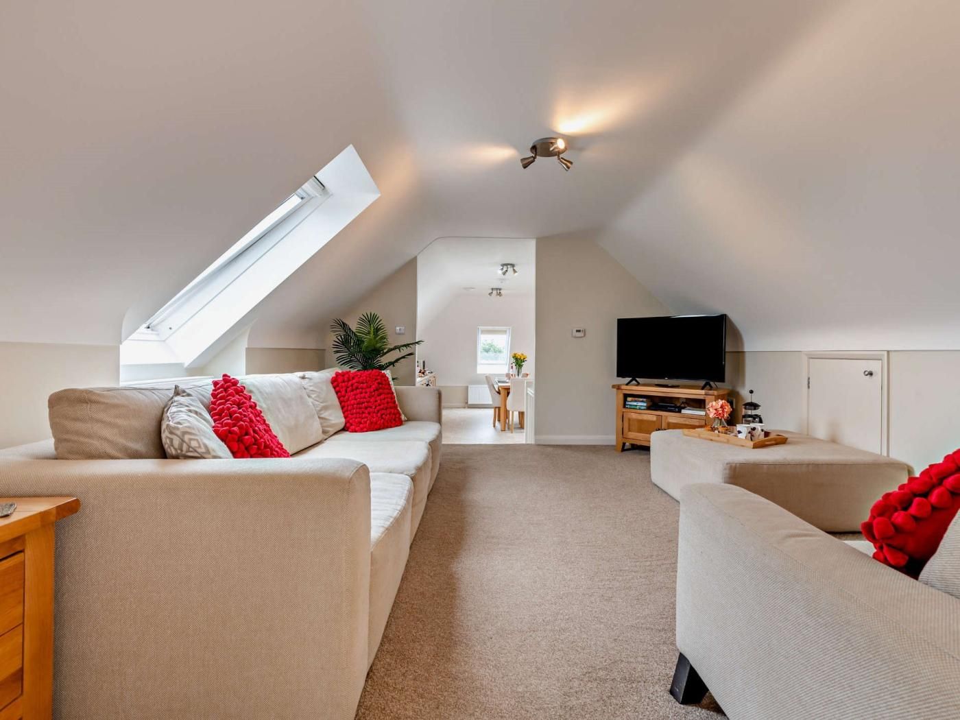 Uma sala de estar moderna no estilo loft, com teto alto, claraboia, TV de tela plana e área de jantar.