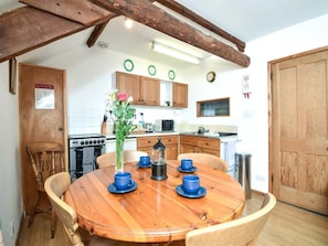 A wooden dining table with four blue cups, a vase with flowers, and a wooden chair. - 3 Bed in Stocksfield (oc-32252) (Stocksfield)