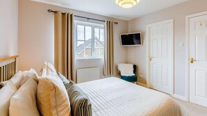 A bedroom with a bed, curtains, a television, and a door. - 3 Bed in Alnwick (oc-36401) (Alnwick)