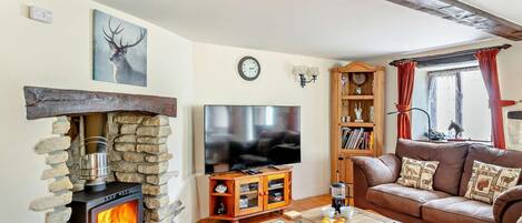 Una sala de estar acogedora con chimenea de piedra, televisor de pantalla plana, sofá de cuero y estantería de madera.