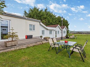 A row of white houses with a grassy yard, a table with chairs, and a red teapot. - 2 Bed in Bristol (oc-37147) (Chew Magna)