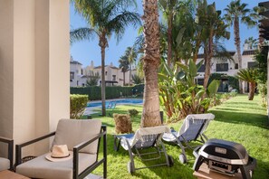 A patio with outdoor furniture, a grill, and a view of a swimming pool and buildings in the background. - Holiday Home 'Casa Thomas II Terraced Corner' with Shared Pool, Wi-Fi and Air Conditioning (Roda)