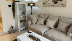 Una sala de estar con un sofá, una mesa de centro, una estantería y una lámpara de pie.