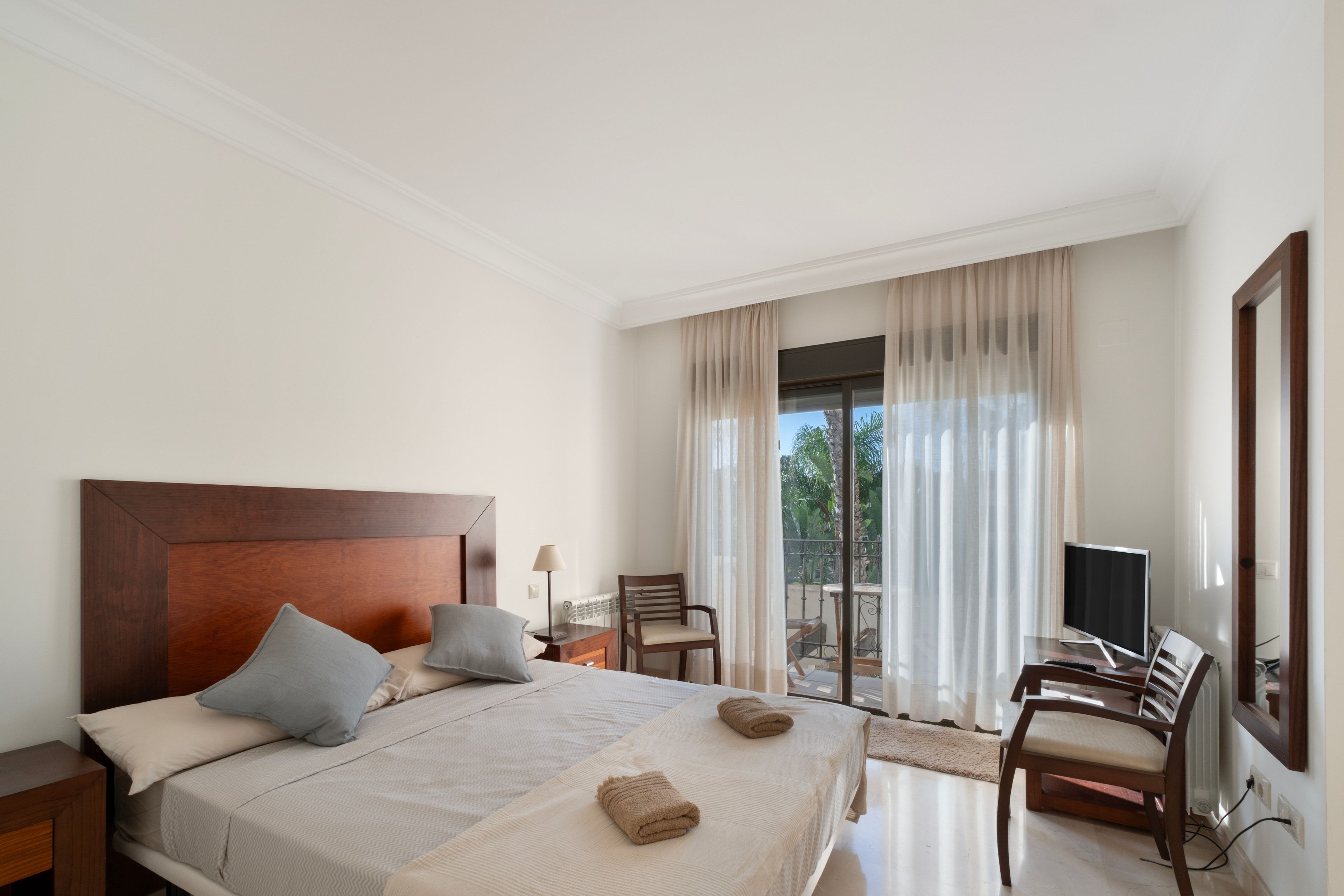 Une chambre d’hôtel équipée d’un lit, d’une télévision, d’une chaise et offrant une vue sur l’extérieur.