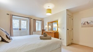 Ein Schlafzimmer mit einem Bett, einer Holzkommode, einem Spiegel und einem Bild an der Wand.