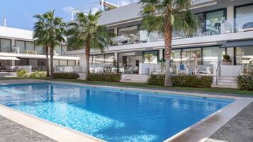 Un hotel moderno con piscina, palmeras y una estructura de dos pisos.