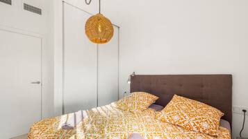 A bedroom with a bed, a hanging light fixture, and a door.
