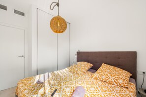 A bedroom with a bed, a hanging light fixture, and a door.
