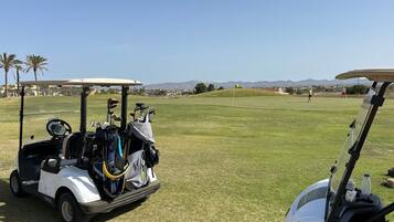 A golf cart with golf clubs and a water bottle on the cart.