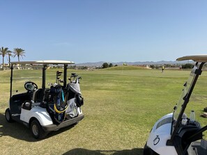Un carrito de golf con palos de golf y una botella de agua encima.