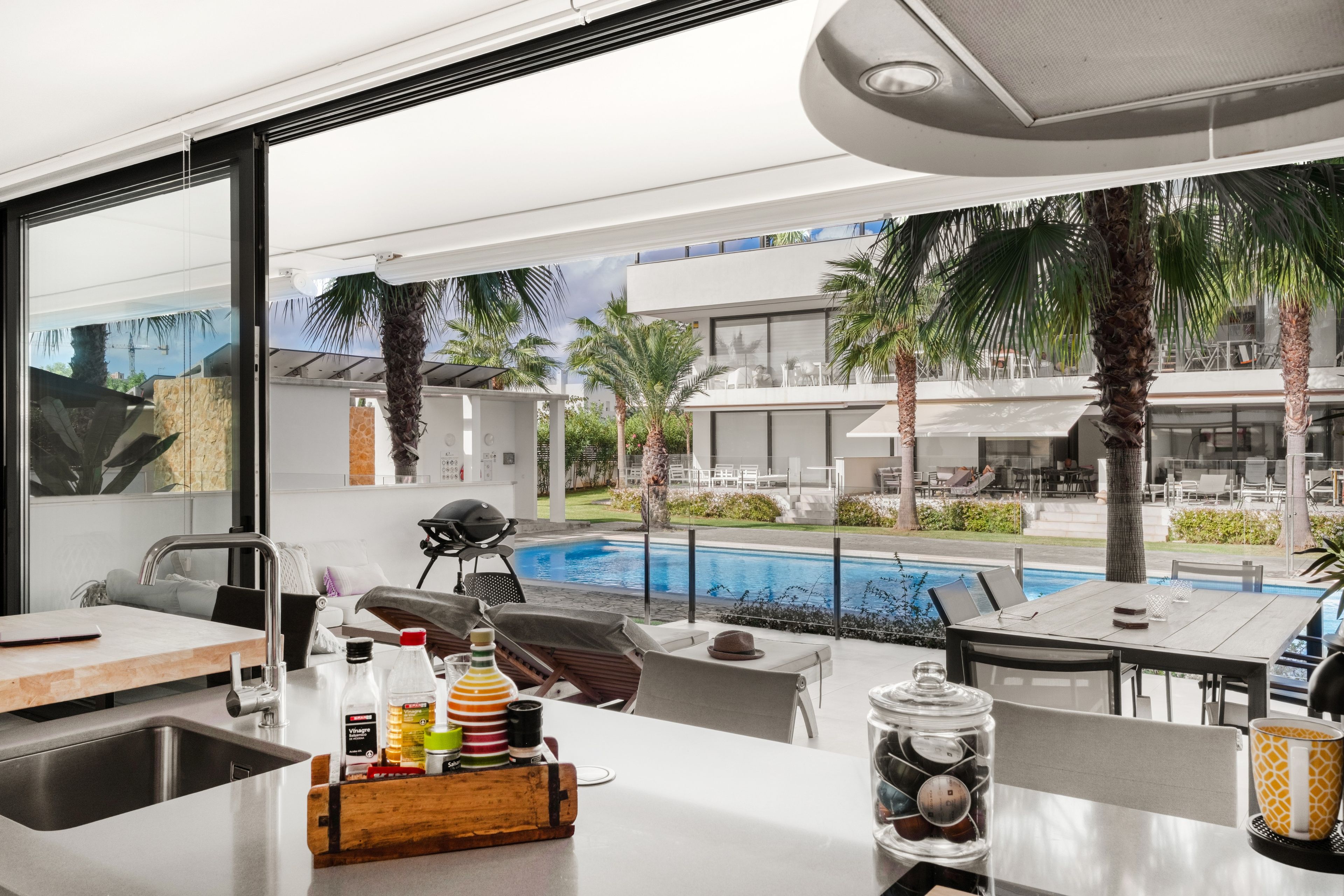Eine moderne Küche mit Blick auf einen Pool und Palmen.