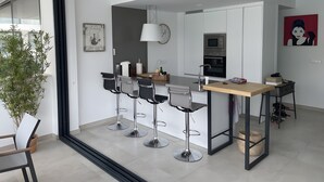 Une cuisine moderne dotée d’un îlot central, de tabourets de bar et d’une table à manger.