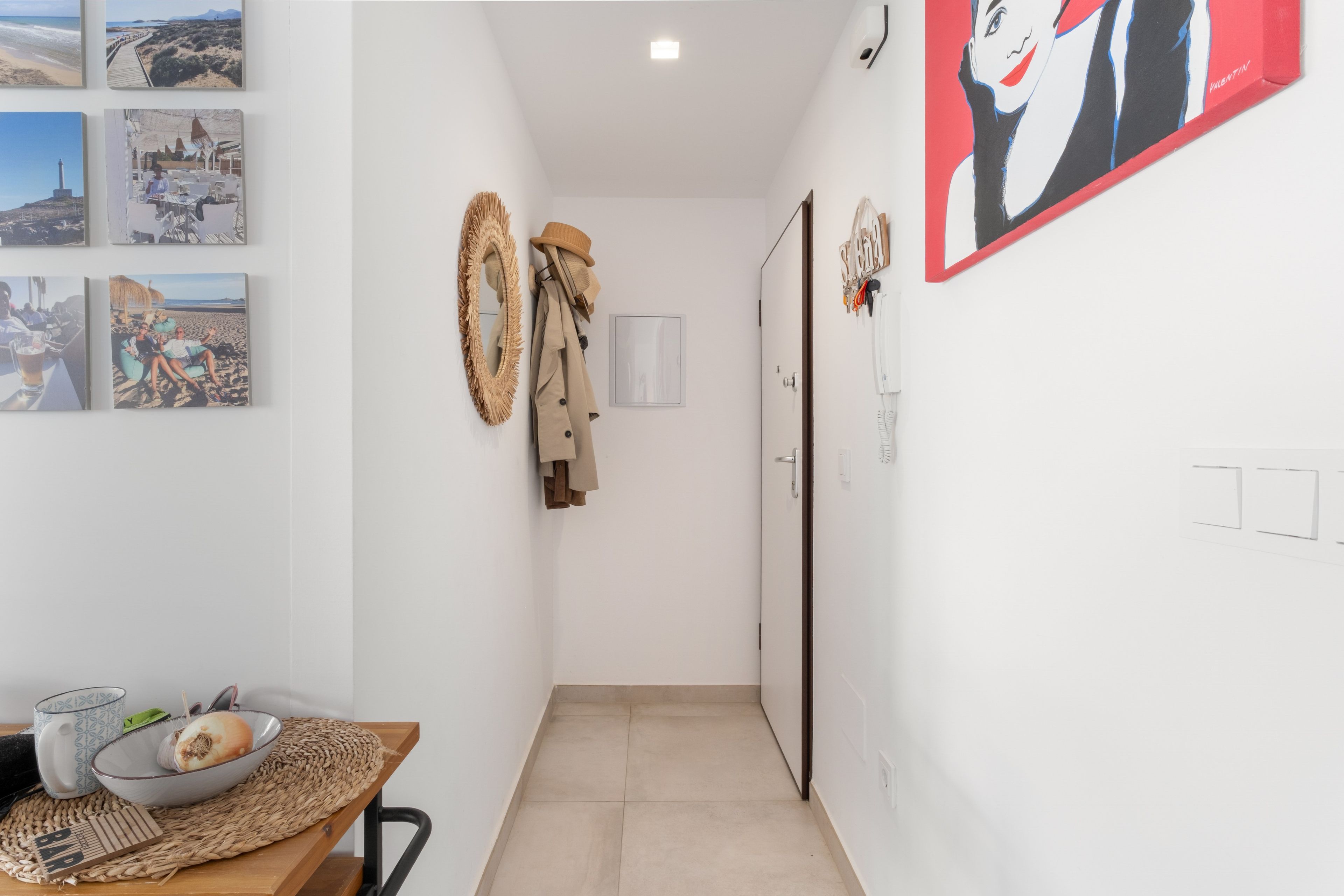 Un couloir qui comprend un coin repas avec une table, un bol, une tasse, un set de table en fibres tressées et une chaise.