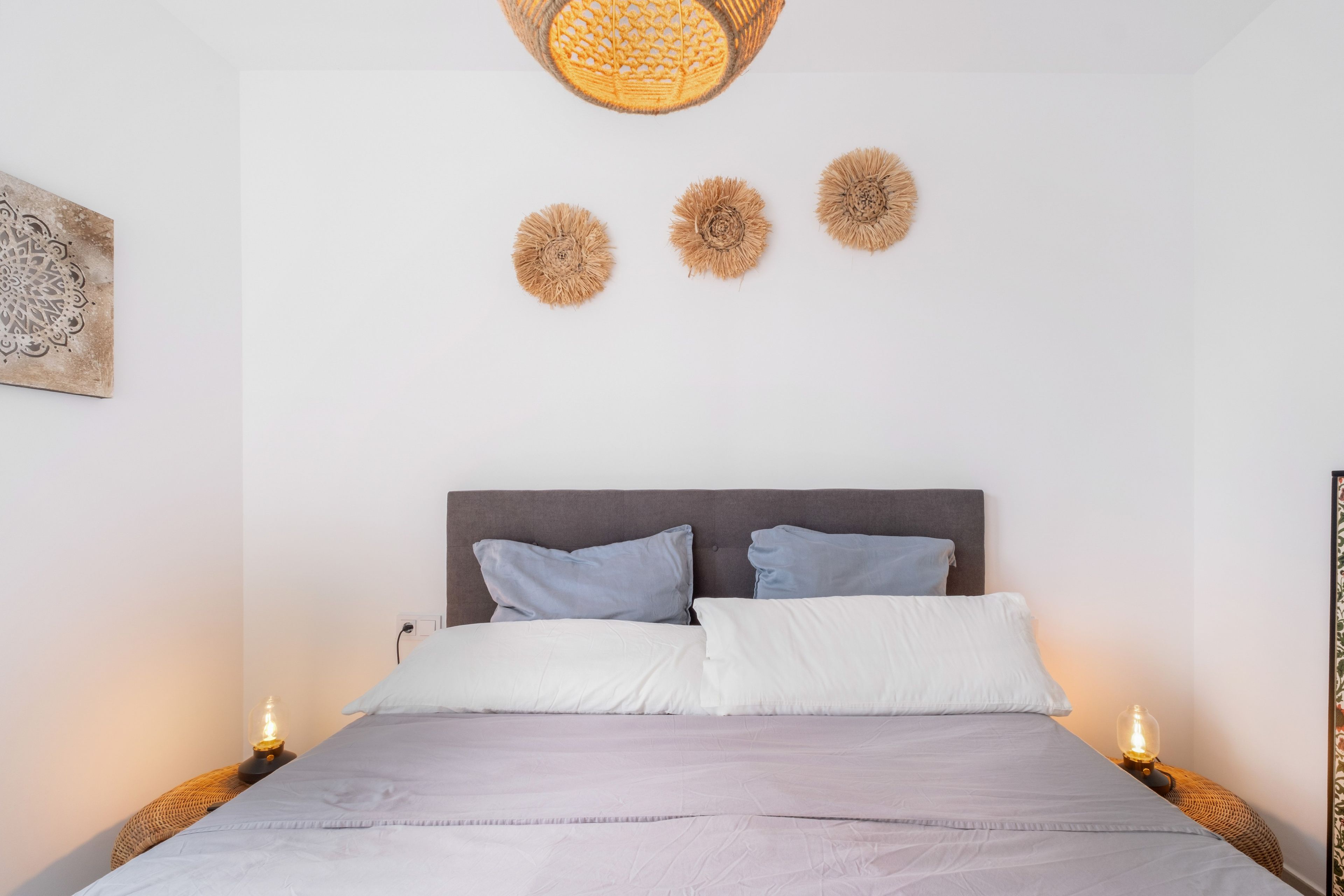 Un dormitorio con una cama, dos lámparas de noche y tres adornos de pared.
